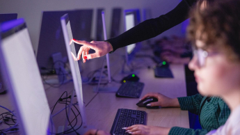 Grafika i multimedia | Studia I stopnia we Wrocławiu | Uniwersytet Dolnośląski DSW we Wrocławiu: Grafika główna: Inżynier aplikacji i systemów chmurowych - studentka wskazująca na ekran monitoru