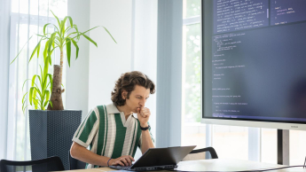 Analityka internetowa z elementami AI | Studia I stopnia we Wrocławiu | Uniwersytet Dolnośląski DSW we Wrocławiu: Grafika główna: Informatyka - student zastanawiający się nad zadaniem informatycznym