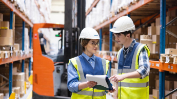 Logistyka | Studia I stopnia we Wrocławiu | Uniwersytet Dolnośląski DSW we Wrocławiu: Studenci logistyki w kamizelkach odblaskowych i kaskach, w magazynie