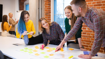 Wyniki wyszukiwania | Uniwersytet Dolnośląski DSW we Wrocławiu: Grupa studentów rozpisująca projekt na biurku.