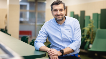 Sztuczna Inteligencja w HR | Studia I stopnia we Wrocławiu | Uniwersytet Dolnośląski DSW we Wrocławiu: mężczyzna w niebieskiej koszuli siedzący przy zielonym stoliku