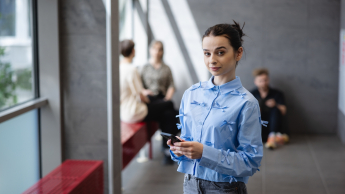 Public relations | Studia I stopnia we Wrocławiu | Uniwersytet Dolnośląski DSW we Wrocławiu: studentka w niebieskiej koszuli z telefonem w ręku