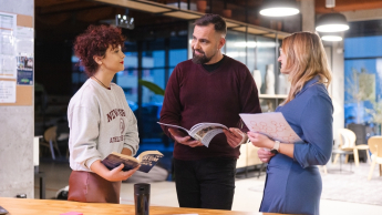 Nowoczesne przywództwo, zarządzanie oparte na danych i skuteczne projekty – liderzy Publicznych Służb Zatrudniania w działaniu | Studia podyplomowe we Wrocławiu | Uniwersytet Dolnośląski DSW we Wrocławiu: trójka studentów stojąca przy biurko z notatkami