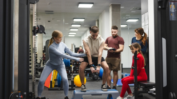 Coaching sportowy | Studia I stopnia we Wrocławiu | Uniwersytet Dolnośląski DSW we Wrocławiu: zajęcia sportowe, student podnosi ciężarek na stepie