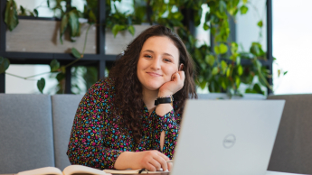 Data analytics i badanie rynku | Studia I stopnia we Wrocławiu | Uniwersytet Dolnośląski DSW we Wrocławiu: studentka w kręconych włosach siedząca przy laptopie i notatniku