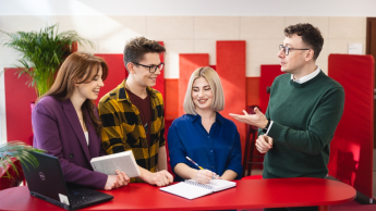 Wyniki wyszukiwania | Uniwersytet Dolnośląski DSW we Wrocławiu: Troje studentów wraz z wykładowcą stoją przy czerwonym stoliku