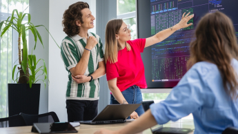 troje studentów analizują dane wyświetlone na tablicy interaktywnej