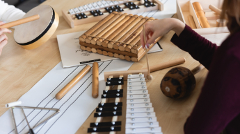 Integracja sensoryczna i psychomotoryka | Uniwersytet Dolnośląski DSW we Wrocławiu: instrumenty leżące na stole: cymbałki, trójkąt, tamburyno