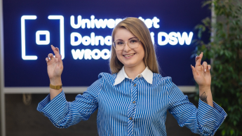 Wyniki wyszukiwania | Uniwersytet Dolnośląski DSW we Wrocławiu: kobieta w niebieskiej koszuli uśmiecha się i zaplata palce.