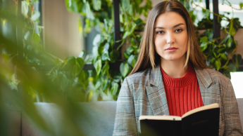 Prawne kompetencje managera | Studia podyplomowe we Wrocławiu | Uniwersytet Dolnośląski DSW we Wrocławiu: studentka z książką