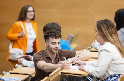 Podcasty | Uniwersytet Dolnośląski DSW we Wrocławiu: Główna grafika: Maturzyści - studenci siedzący razem na auli