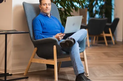 Aktualności | Uniwersytet Dolnośląski DSW we Wrocławiu: Mężczyzna siedzący na krześle oraz trzymający laptopa na kolanach