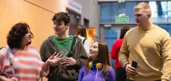 Studia I stopnia we Wrocławiu | Uniwersytet Dolnośląski DSW we Wrocławiu: Główna grafika: Studia I stopnia - studenci wspólnie idący przez korytarz