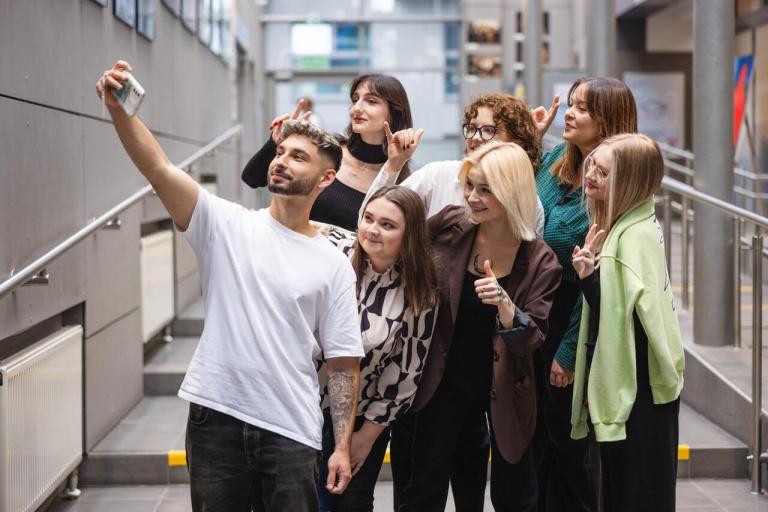 Maturzyści | Uniwersytet Dolnośląski DSW we Wrocławiu: Główna grafika: Maturzyści - grupa studentów pozująca do zdjęcia robionego telefonem