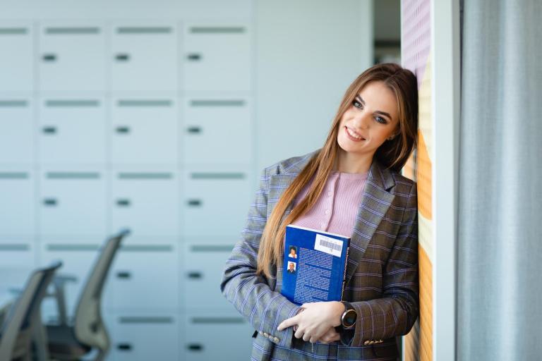 Dolnośląski Program Pomocy Stypendialnej dla uczniów szczególnie uzdolnionych w zakresie przedmiotów ścisłych i zagrożonych wykluczeniem społecznym | Uniwersytet Dolnośląski DSW we Wrocławiu: Grafika główna: Zniżki i dofinansowanie szkolenia i kursy - studentka opierająca się o ścianę