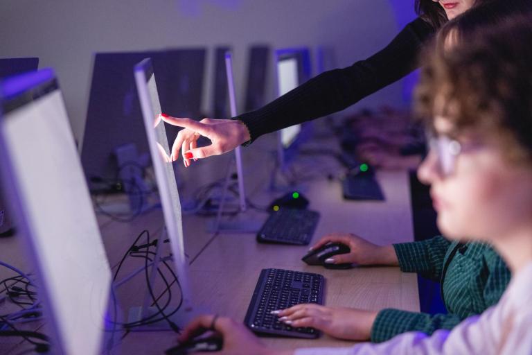 Projektowanie systemów informatycznych i analiza danych | Studia I stopnia we Wrocławiu | Uniwersytet Dolnośląski DSW we Wrocławiu: Grafika główna: Inżynier aplikacji i systemów chmurowych - studentka wskazująca na ekran monitoru