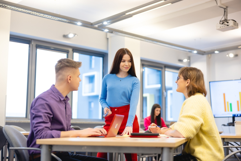 Zarządzanie kulturą organizacyjną | Studia I stopnia we Wrocławiu | Uniwersytet Dolnośląski DSW we Wrocławiu: troje studentów wspólnie pracująca nad zadaniem przy biurku