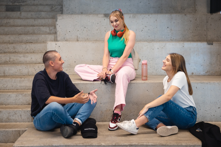 Pedagogika korekcyjna (terapia pedagogiczna) – dla pedagogów specjalnych | Studia podyplomowe we Wrocławiu | Uniwersytet Dolnośląski DSW we Wrocławiu: studenci siedzący na schodkach na dworze