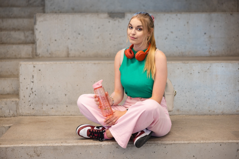 Coaching sportowy | Studia I stopnia we Wrocławiu | Uniwersytet Dolnośląski DSW we Wrocławiu: studentka siedząca na schodkach i trzymająca butelkę z wodą
