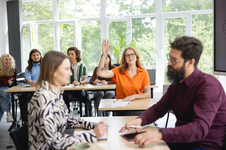 HR Manager | Studia I stopnia we Wrocławiu | Uniwersytet Dolnośląski DSW we Wrocławiu: studentka w pomarańczowej koszulce zgłasza się podczas zajęć