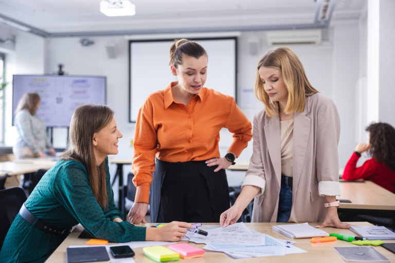 Akademia przywództwa kobiet | Studia podyplomowe we Wrocławiu | Uniwersytet Dolnośląski DSW we Wrocławiu: trzy studentki wspólnie pracujące nad projektem