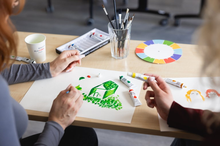 Arteterapia | Studia podyplomowe we Wrocławiu | Uniwersytet Dolnośląski DSW we Wrocławiu: studentki malujące zielony domek farbkami