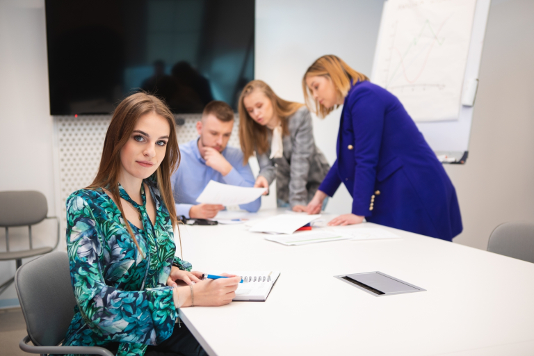 Customer Experience | Studia I stopnia we Wrocławiu | Uniwersytet Dolnośląski DSW we Wrocławiu: Wrocław: studenci pracujący nad projektem, na pierwszym planie widnieje studentka, robiąca notatki w koszulce w zielone rośliny