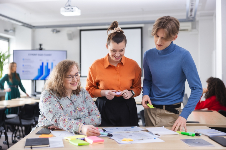 Controlling i analiza finansowa | Studia I stopnia we Wrocławiu | Uniwersytet Dolnośląski DSW we Wrocławiu: Grupa 3 studentów na zajęciach warsztatowych, omawiają materiały które leżą na stole