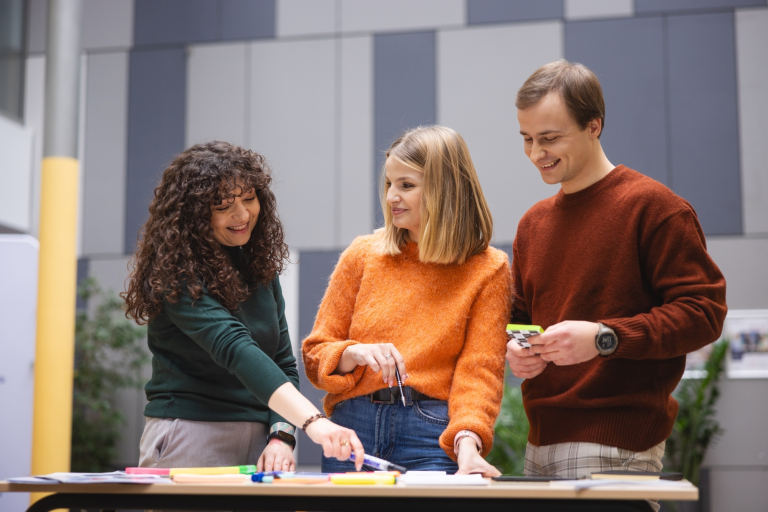 Communication design z elementami AI | Studia I stopnia we Wrocławiu | Uniwersytet Dolnośląski DSW we Wrocławiu: Grupa osób stojąca przy stole