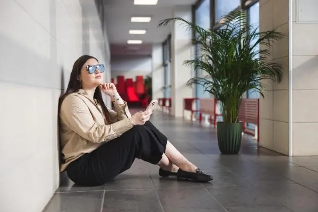 Poznaj nas | Uniwersytet Dolnośląski DSW we Wrocławiu: Studentka siedząca przy ścianie.