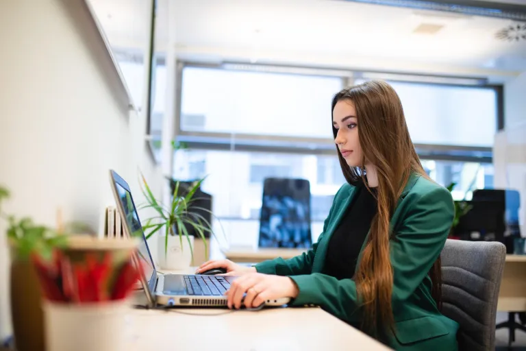 Stypendia i zniżki - studia I stopnia | Uniwersytet Dolnośląski DSW we Wrocławiu: Główna grafika: Stypendia i zniżki - młoda kobieta siedząca przy komputerze