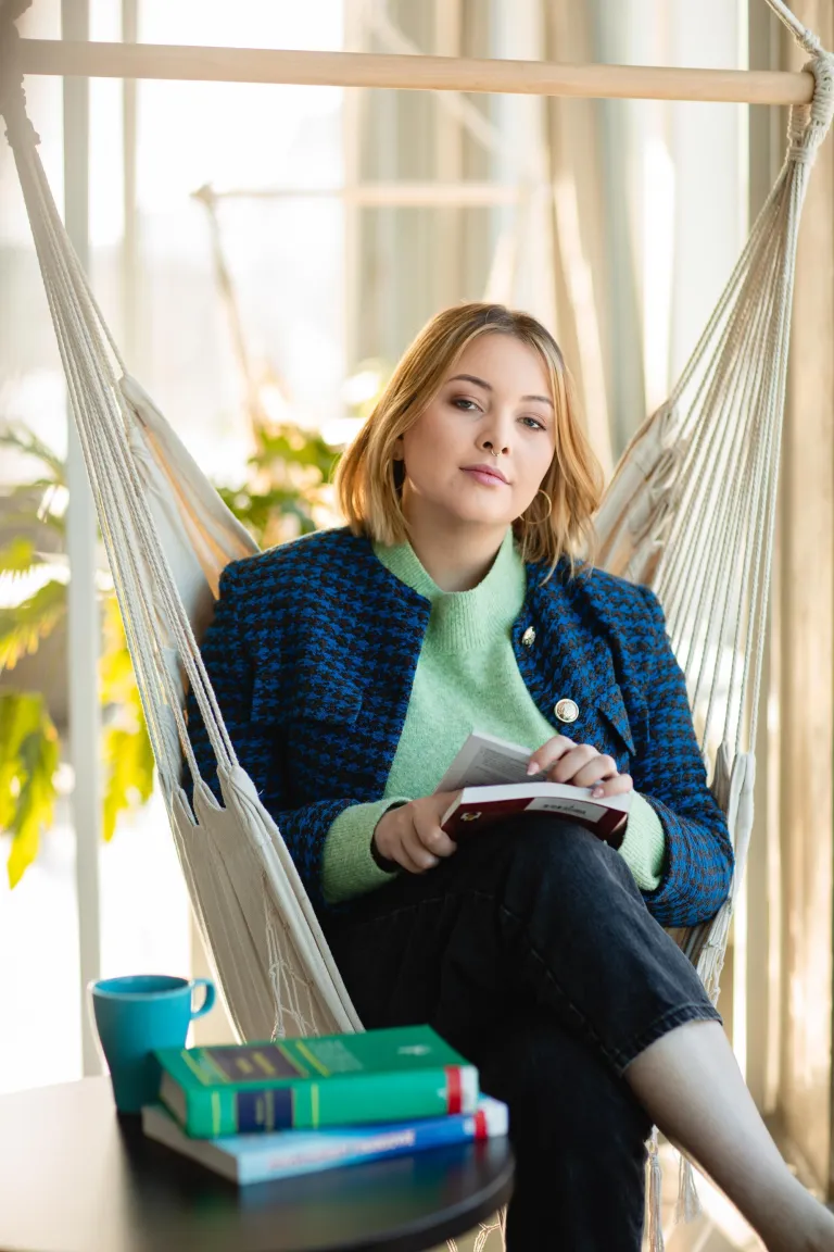 Poznaj nas | Uniwersytet Dolnośląski DSW we Wrocławiu: Zdjęcie siedzącej studentki z książkami.