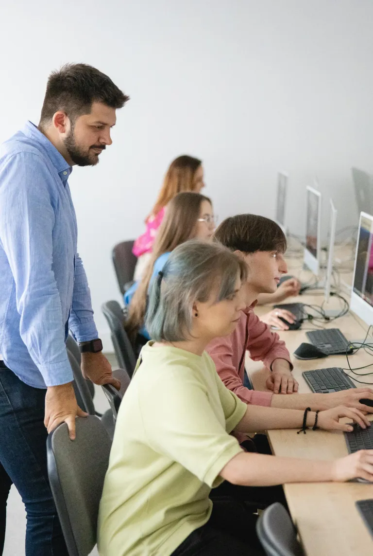 Inżynier aplikacji i systemów chmurowych | Studia I stopnia we Wrocławiu | Uniwersytet Dolnośląski DSW we Wrocławiu: Wykładowca ze studentami, na zajęciach z informatyki
