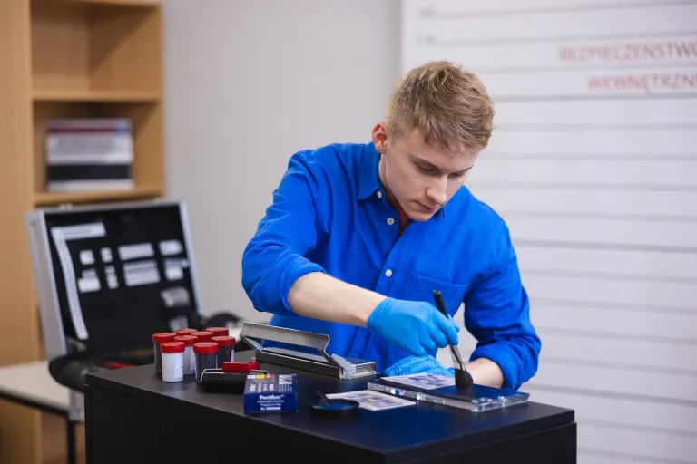 Kryminologia z kryminalistyką | Studia I stopnia we Wrocławiu | Uniwersytet Dolnośląski DSW we Wrocławiu: student z niebieskiej koszuli, ściąga odciski palców