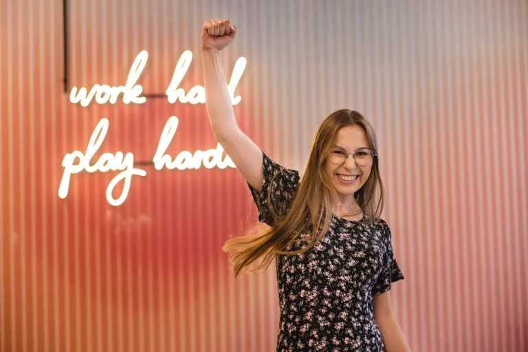 Coaching sportowy | Studia I stopnia we Wrocławiu | Uniwersytet Dolnośląski DSW we Wrocławiu: uśmiechnięta studentka podnosi rękę do góry w geście wiwatu