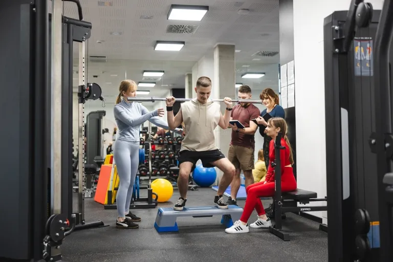 Asystent diagnostyki sportowej | Studia I stopnia we Wrocławiu | Uniwersytet Dolnośląski DSW we Wrocławiu: zajęcia sportowe na siłowni, student podnosi sztangę