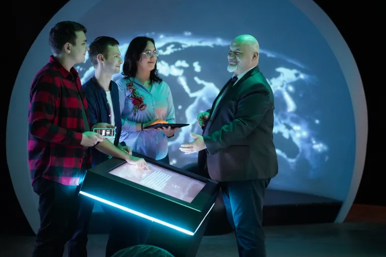 Zarządzanie cyberbezpieczeństwem | Studia I stopnia we Wrocławiu | Uniwersytet Dolnośląski DSW we Wrocławiu: studenci z wykładowcą na zajęciach z bezpieczeństwa narodowego, w tle znajduje się mapa świata