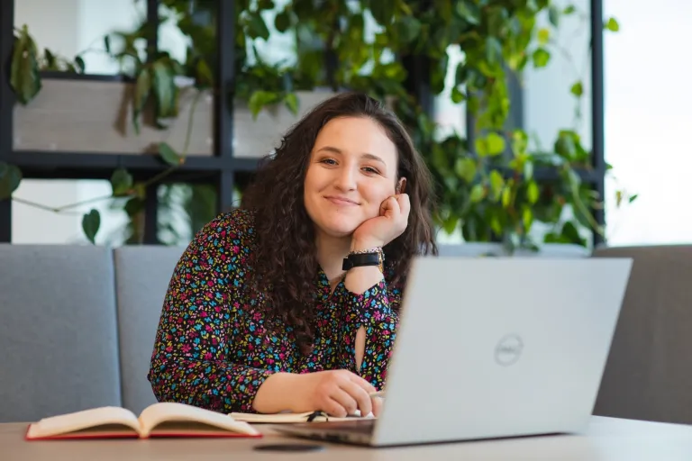 Sztuczna Inteligencja w HR | Studia I stopnia we Wrocławiu | Uniwersytet Dolnośląski DSW we Wrocławiu: studentka w kręconych włosach siedząca przy laptopie i notatniku