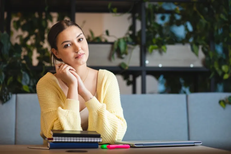 Strefa studenta | Uniwersytet Dolnośląski DSW we Wrocławiu: studentka w żółtym swetrze siedząca przy notatkach
