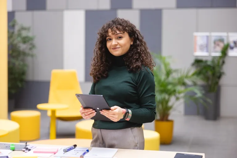 Employer branding z elementami AI | Studia I stopnia we Wrocławiu | Uniwersytet Dolnośląski DSW we Wrocławiu: studentka w zielonym golfie z tabletem w ręku