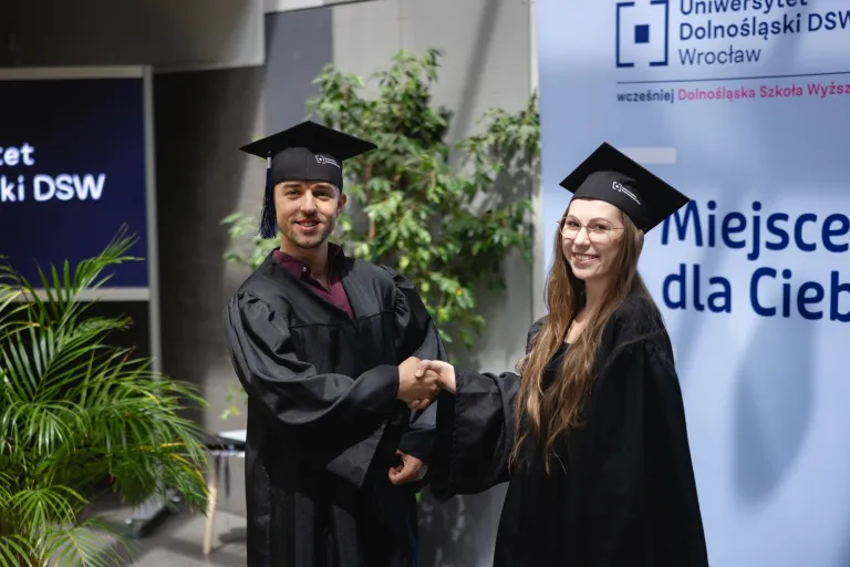 Wyniki konkursu na najlepszą pracę magisterską | Aktualności | Uniwersytet Dolnośląski DSW we Wrocławiu: studenci w togach podający sobie ręcę