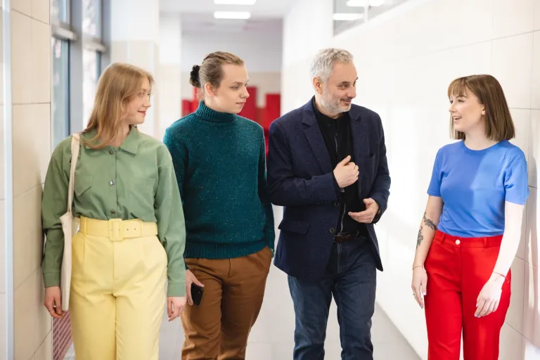 rozmowa wykładowcy ze studentami na korytarzu