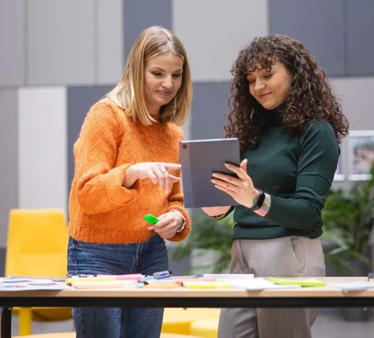 Spotkanie mentoringowe: rozmowy mentorów i mentee | otwarte dla wszystkich | Aktualności | Uniwersytet Dolnośląski DSW we Wrocławiu: dwie studencki oglądające na tablecie notatki
